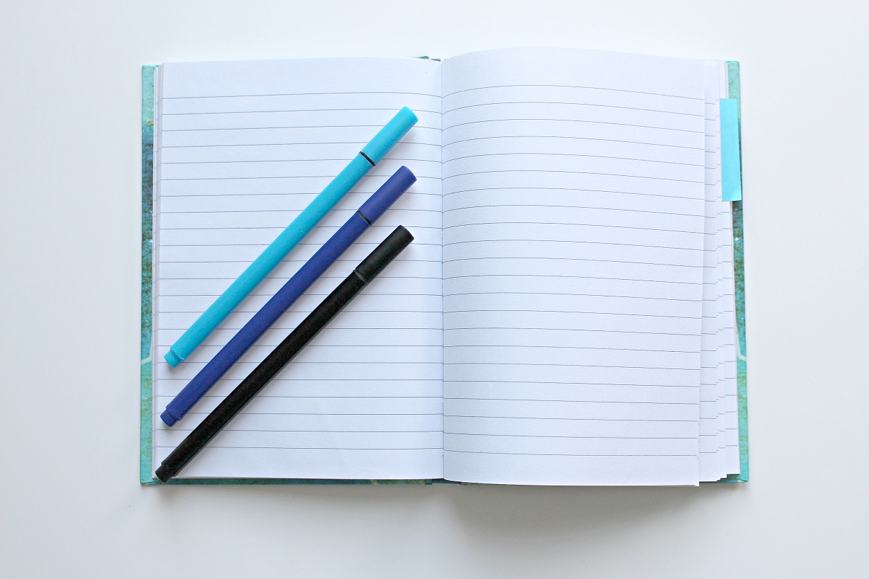 An open notebook with three markers